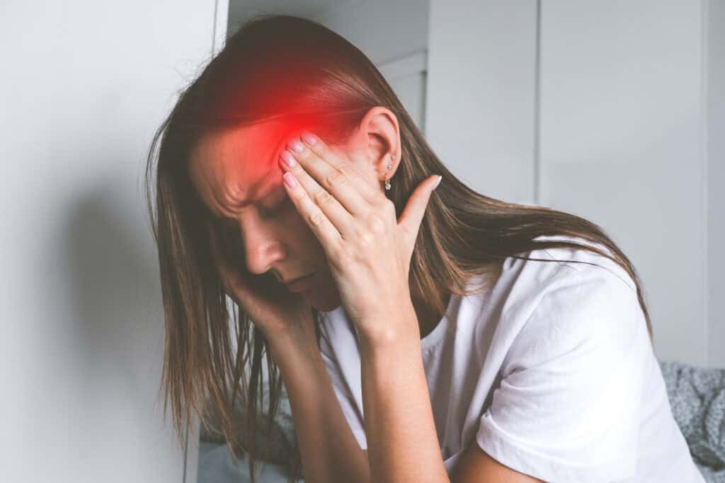 Vrouw met aanval clusterhoofdpijn met handen op het hoofd